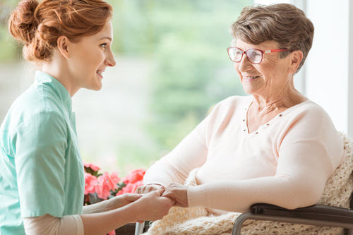 Young nurse holding hands with an elderly woman in a care setting