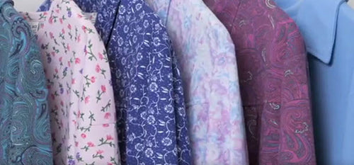 Set of patterned petal back clothing items in shades of pink, blue and purple, hanging on a rack